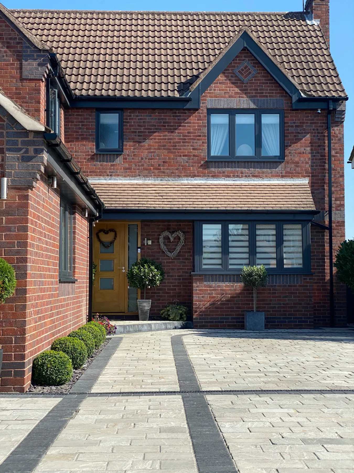 Red-brick house with a new grey block-paved driveway and charcoal border