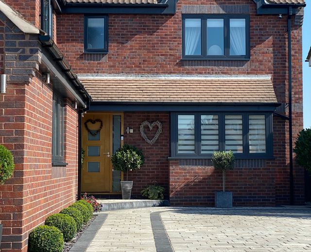 Red-brick house with a new grey block-paved driveway and charcoal border