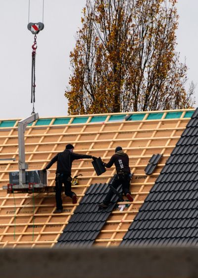 Roofers laying new tiles on battens