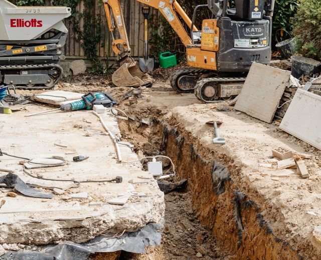 Mini digger and tracked dumper excavating footings in a back garden