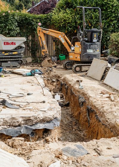 Mini digger and tracked dumper excavating footings in a back garden